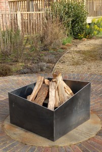 Basalt fire pit from the side. A contemporary modern metal geometric or square firepit.